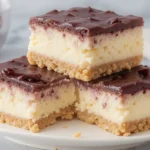 Philadelphia Cheesecake Bars with a creamy filling, chocolate, and raspberry topping.