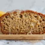 A close-up of a freshly sliced banana bread on a wooden cutting board, showcasing its moist and fluffy texture.